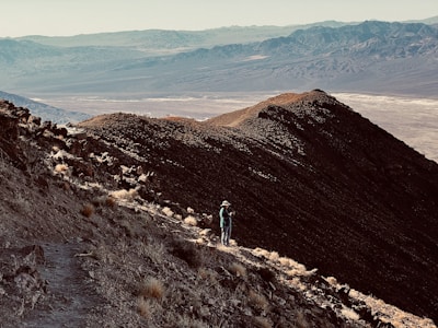 A hiker standing on a mountain peak overlooking a vast landscape.