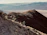 A hiker standing on a rocky mountain peak at sunrise, overlooking a vast valley.