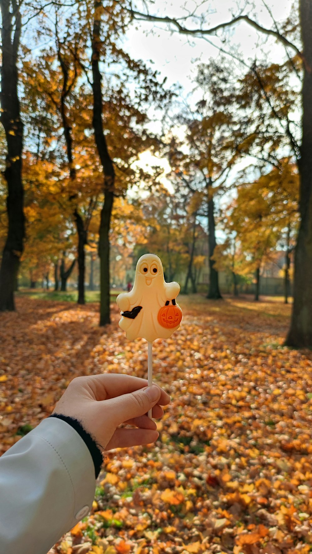 Une personne tenant un faux fantôme sur un bâton dans un parc
