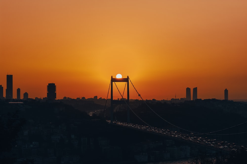the sun is setting over a bridge in a city