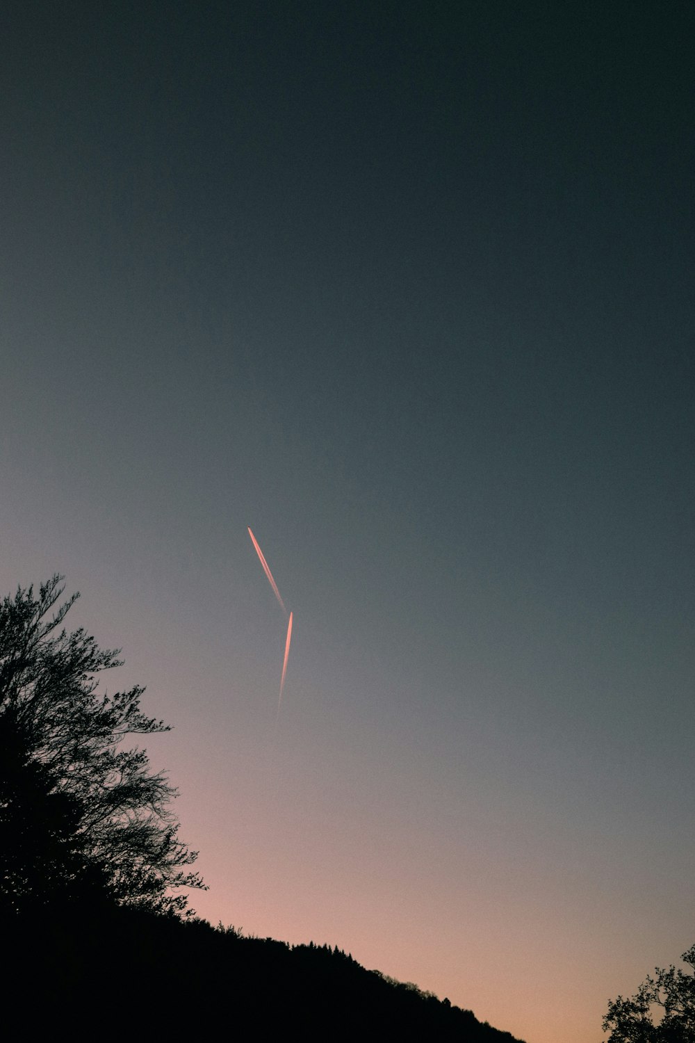 a plane is flying in the sky over a hill