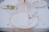 Close-up of a beautifully set table with elegant plates, napkins, and eucalyptus accents.