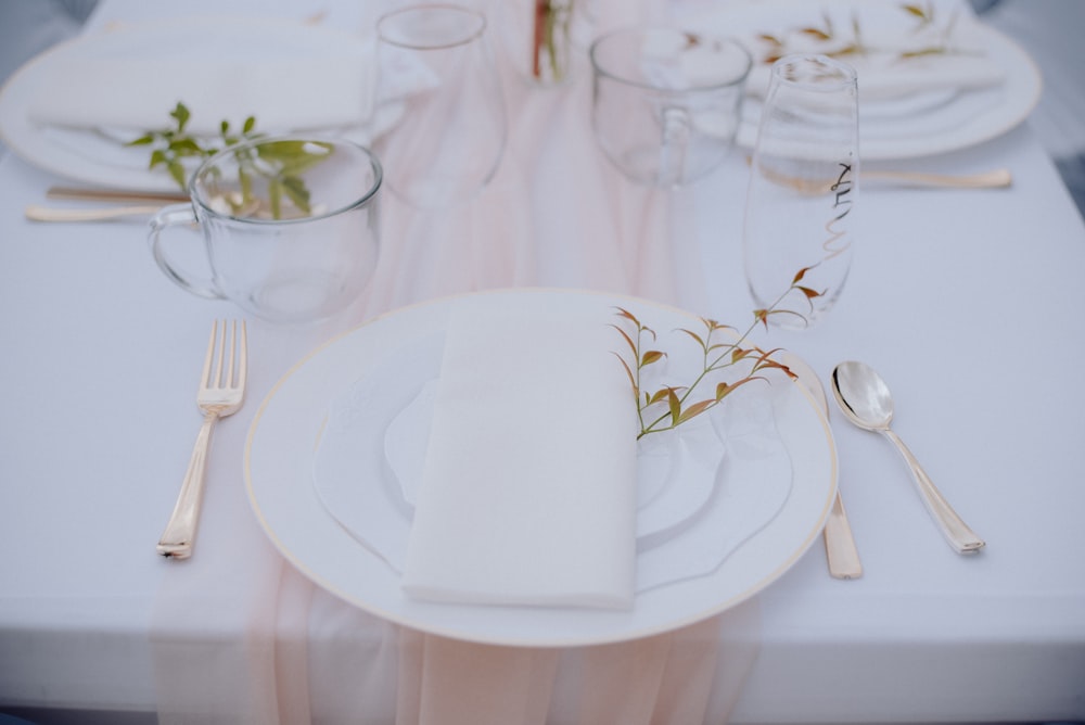 a table set for a formal dinner with white plates and silverware
