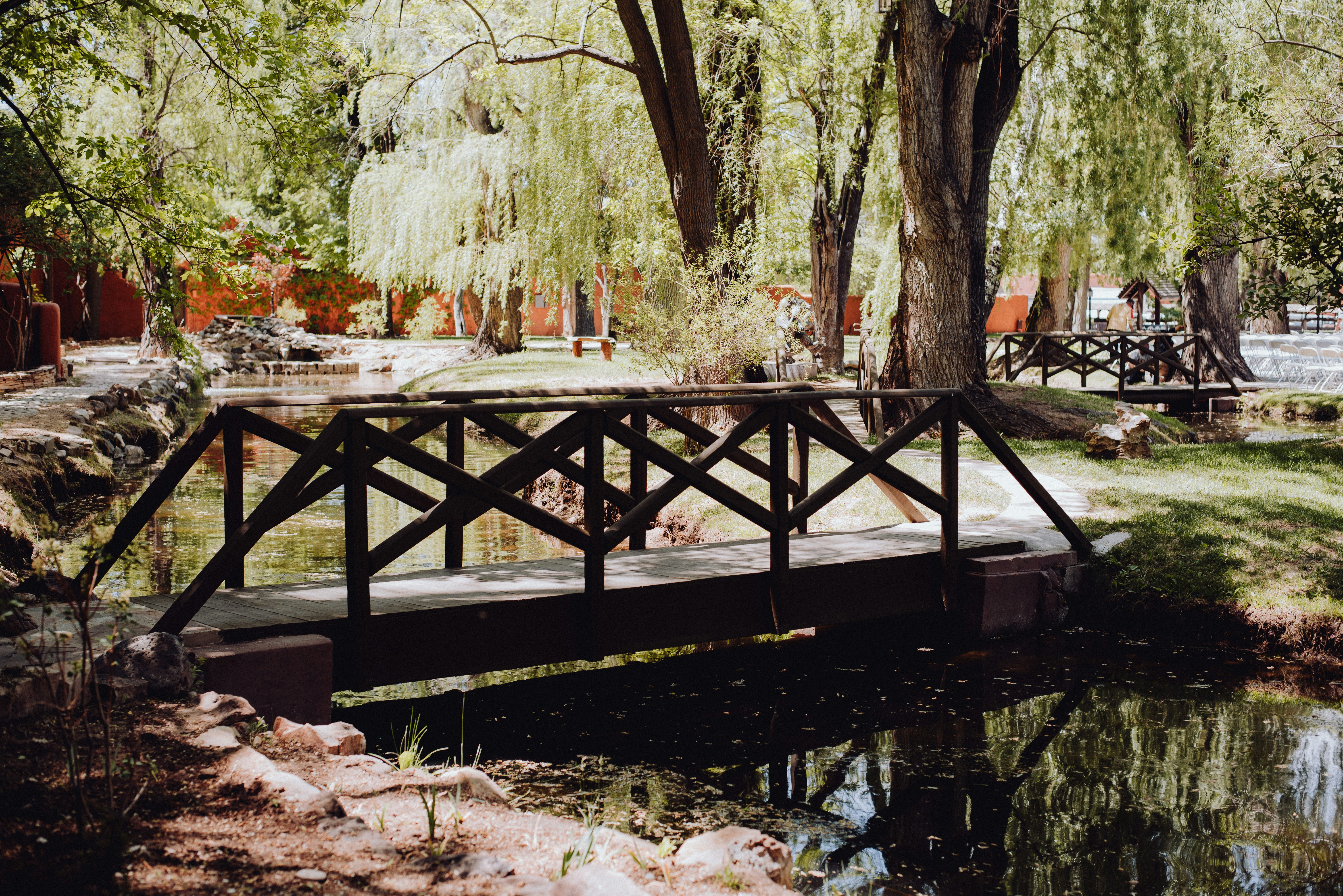 a wooden bridge over a small pond in a park