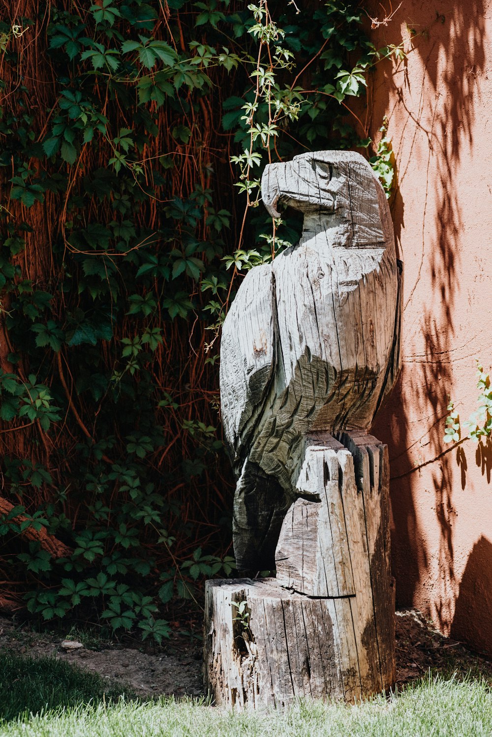 una statua di un uccello seduto sulla cima di un ceppo d'albero