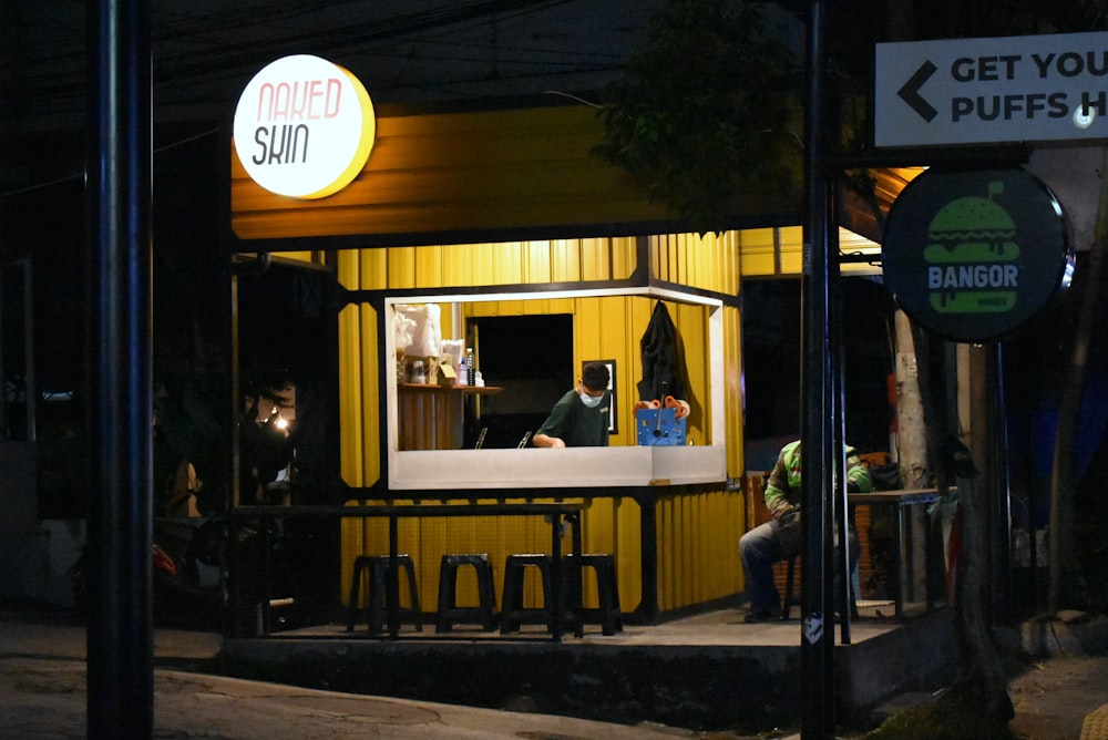 a man sitting at a bar in front of a yellow building