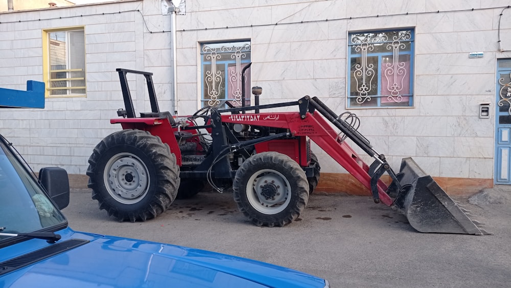 a red tractor parked in front of a building