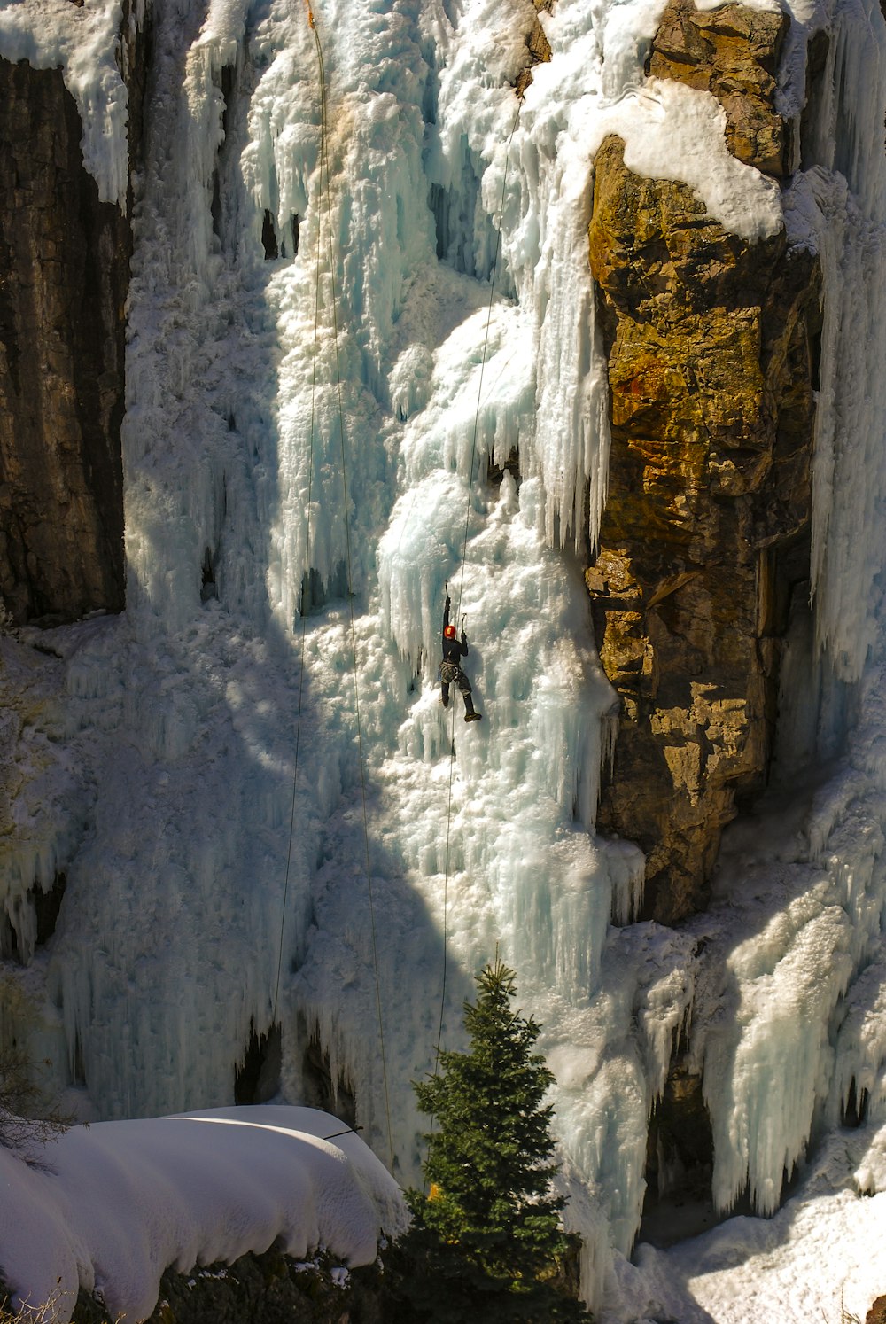 um homem subindo o lado de uma montanha coberta de neve