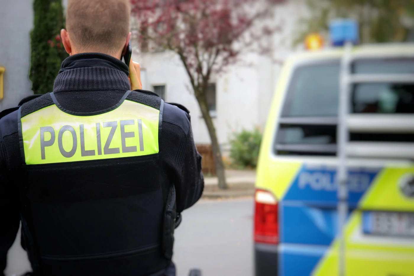 Polizeibeamter von hinten vor einem Streifenwagen als Symbol für freie Heilfürsorge