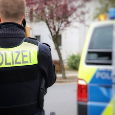 Polizeibeamte (von hinten), im Hintergrund ein Streifenwagen