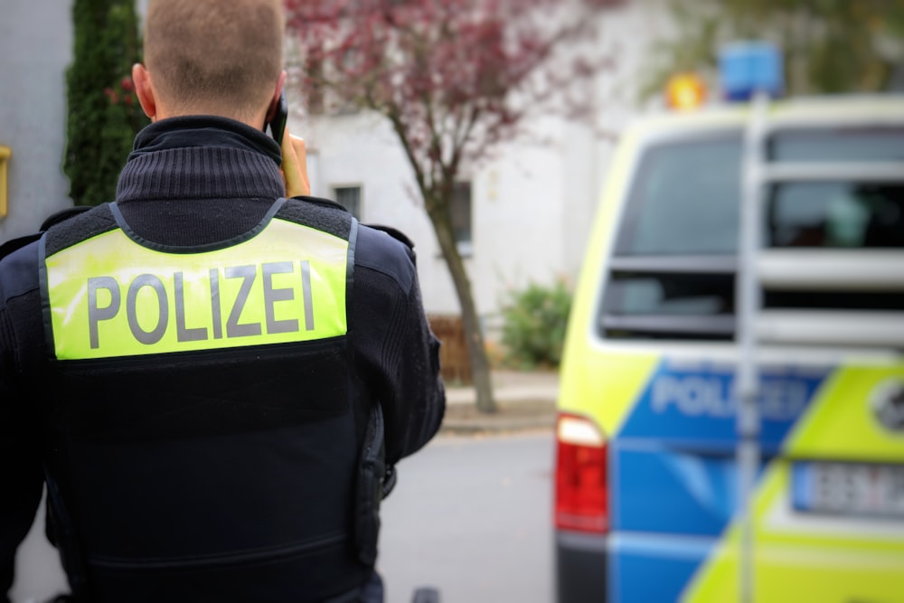 Ein Polizist steht vor einem Polizeiauto