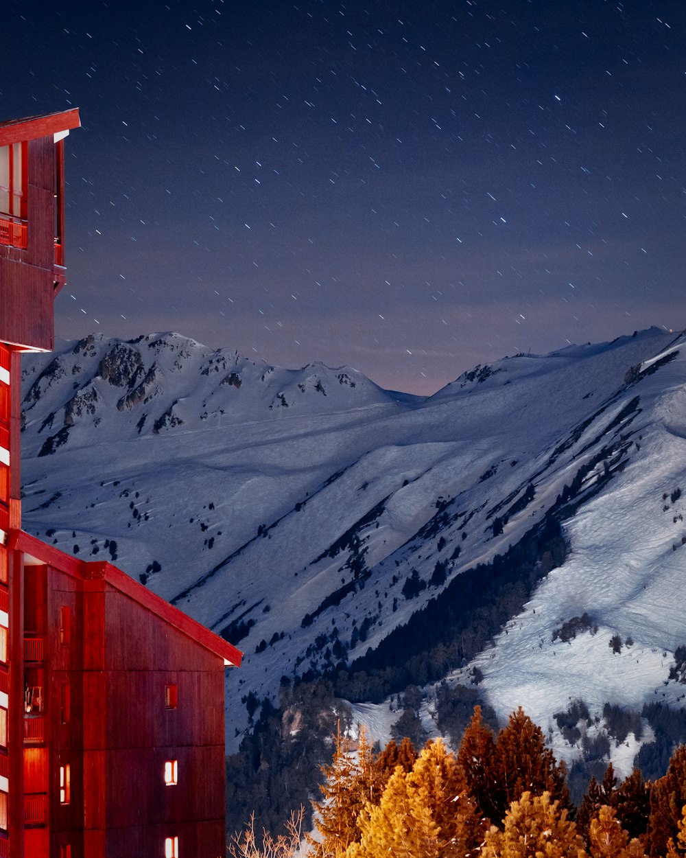 um edifício vermelho alto sentado ao lado de uma montanha coberta de neve