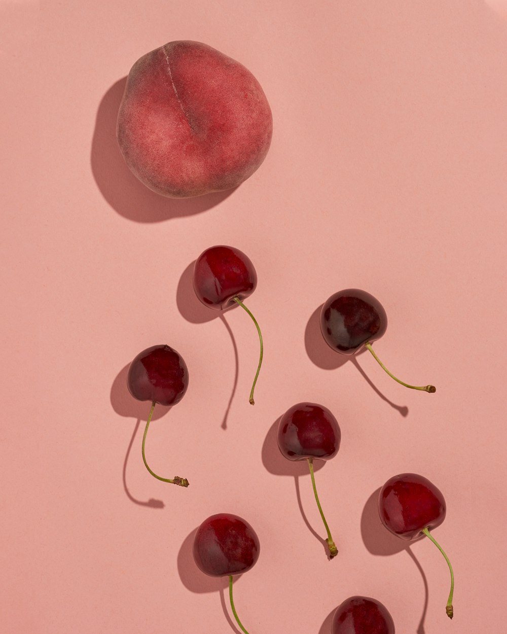 un groupe de cerises assises sur une surface rose