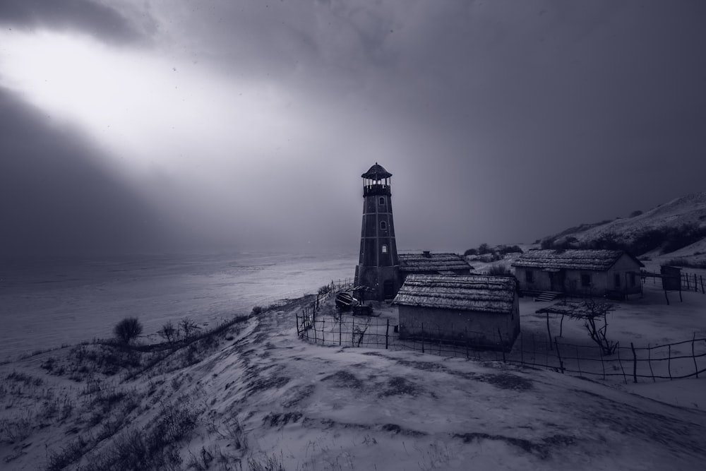 a black and white photo of a lighthouse in the snow