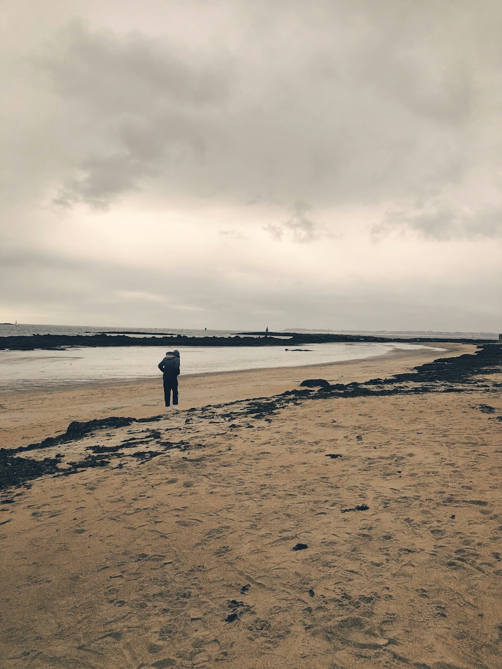 a man standing on top of a sandy beach next to the ocean