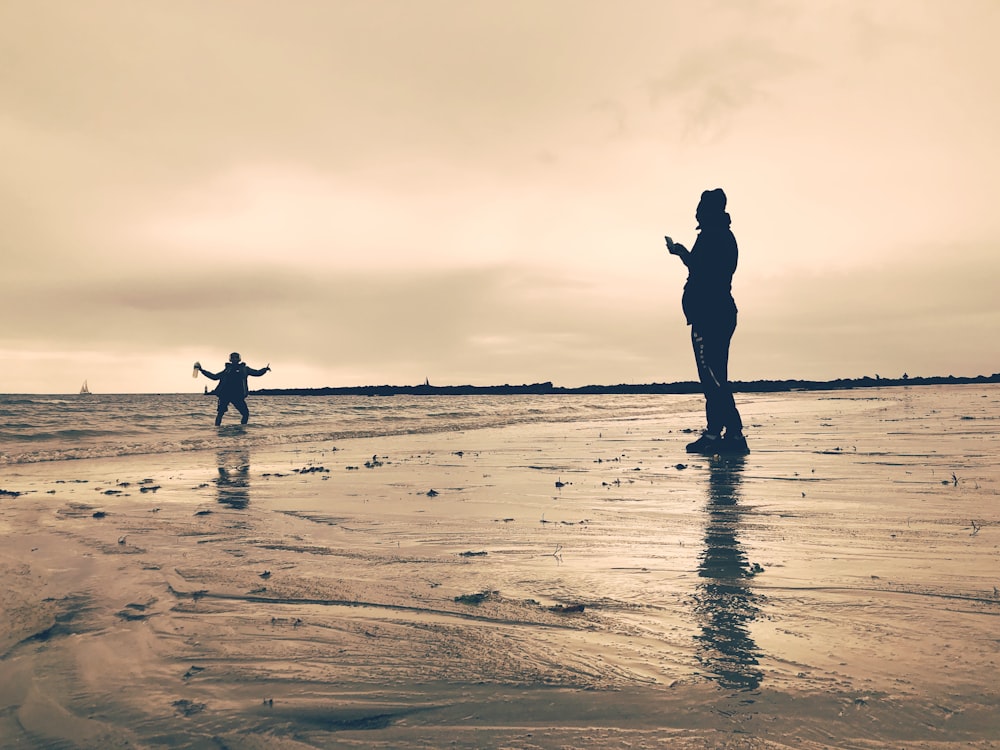 a couple of people standing on top of a beach