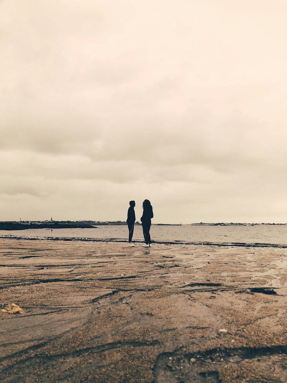 a couple of people standing on top of a sandy beach