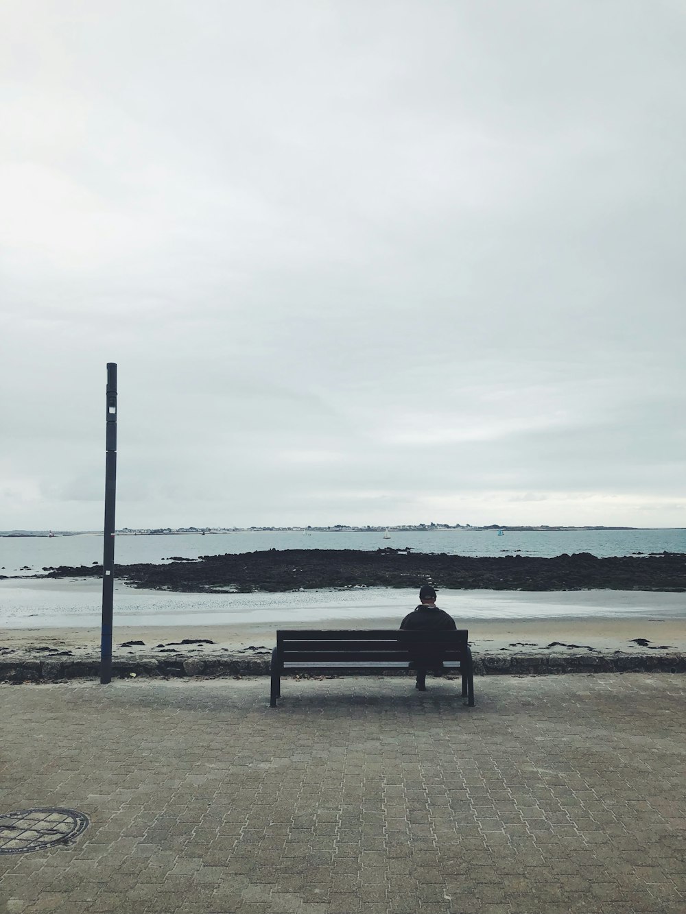 a man sitting on top of a bench next to the ocean