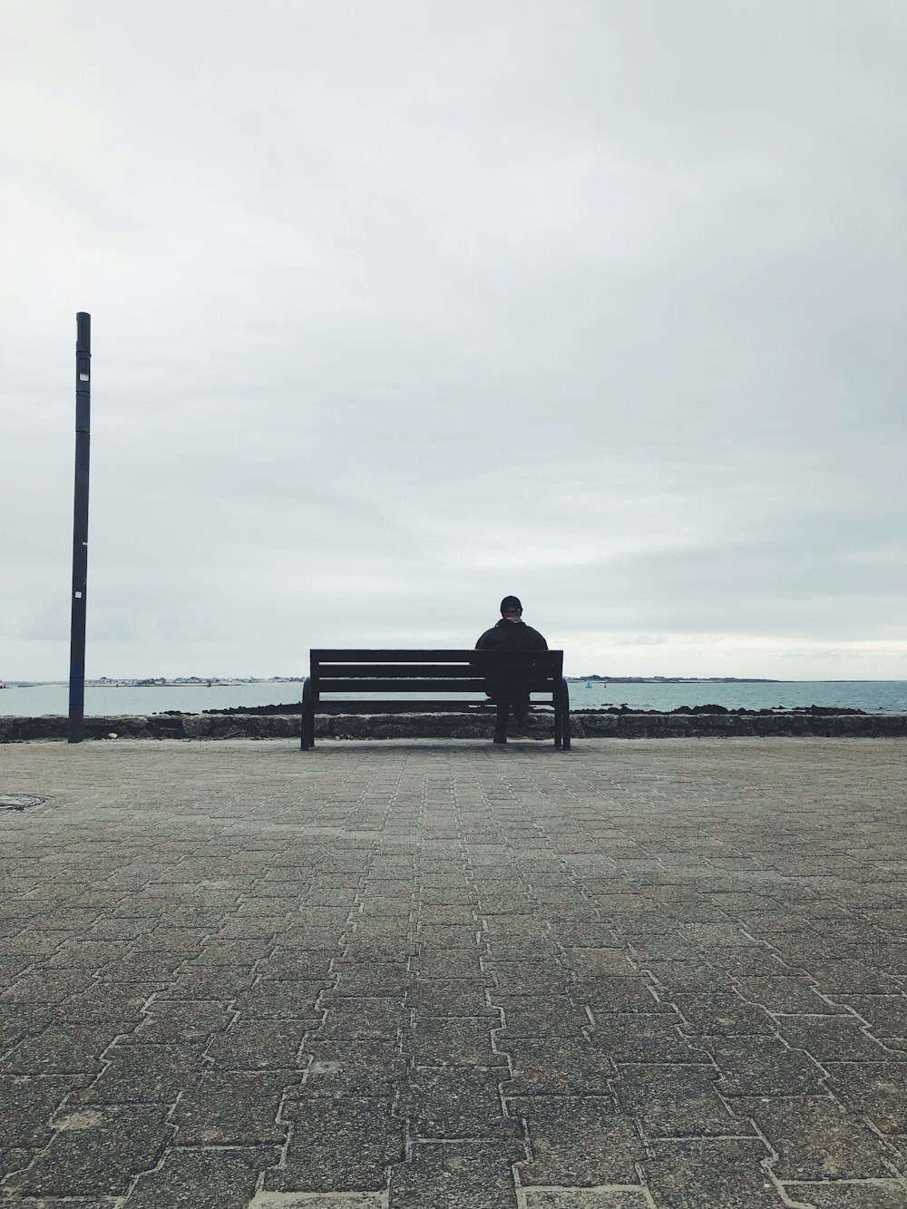 a man sitting on a bench near the ocean