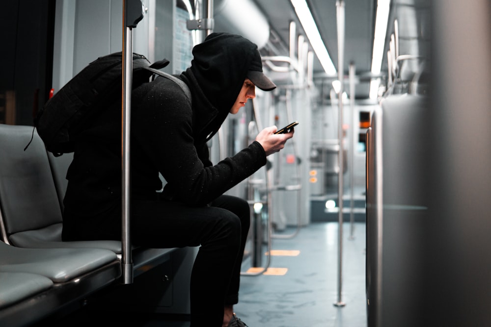 a person sitting on a bus looking at a cell phone