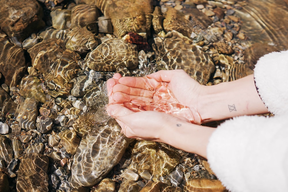 a person holding their hands in a stream of water