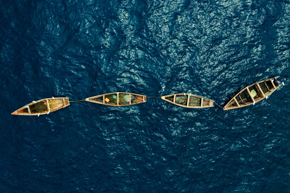 three canoes floating in the ocean on a sunny day