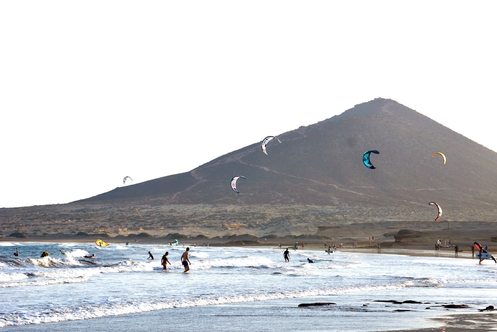 a group of people flying kites on top of a sandy beach