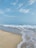 A serene beach scene with soft white sand and gentle waves under a clear blue sky.