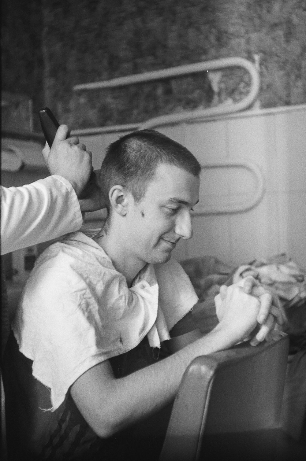 a black and white photo of a man getting his hair cut