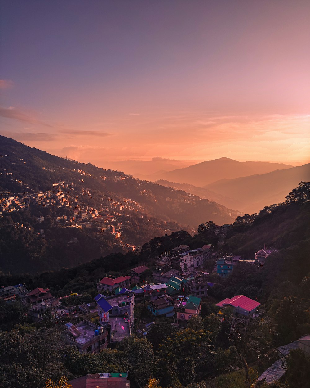 a sunset view of a small town on a hill