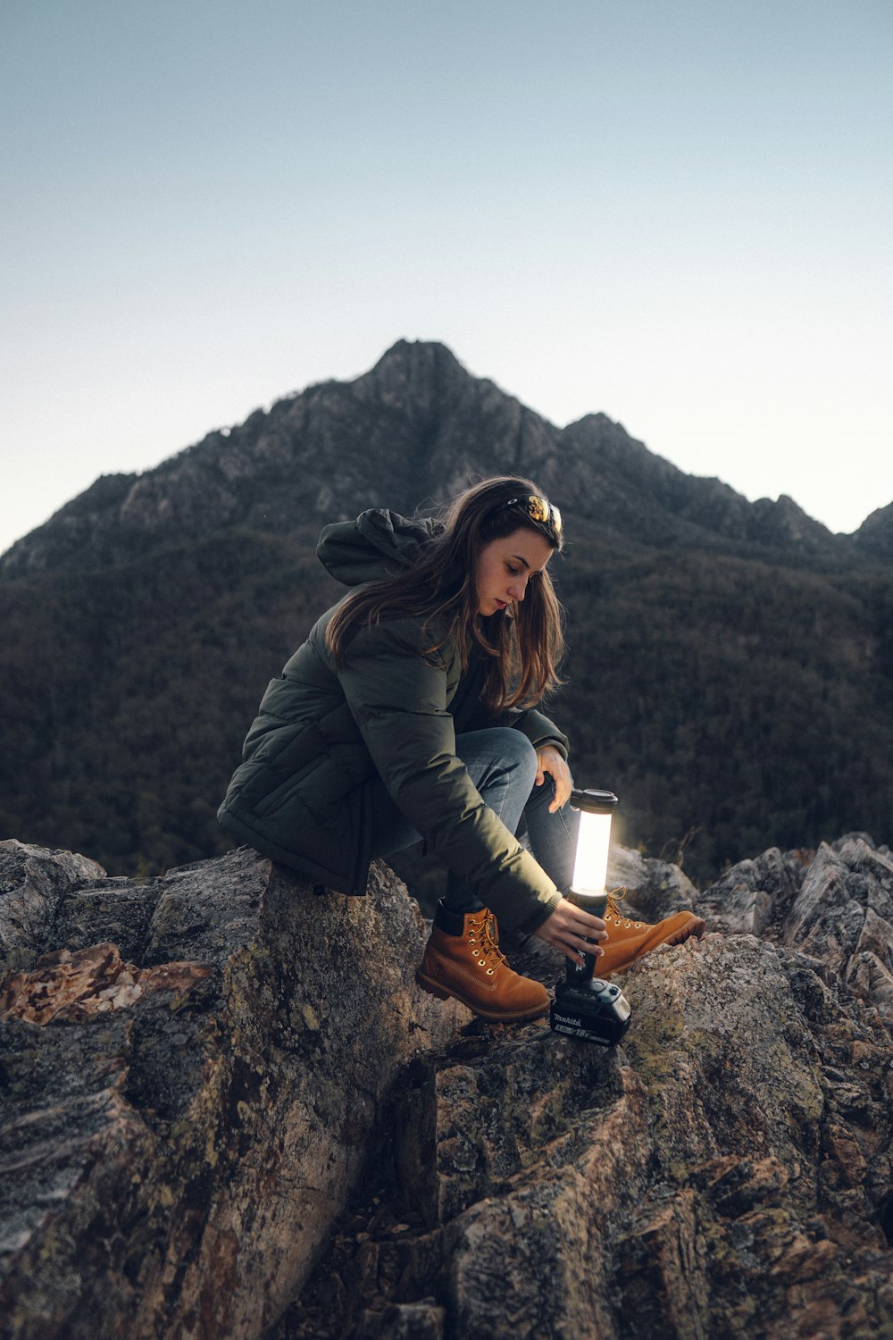 a woman sitting on top of a rock next to a light