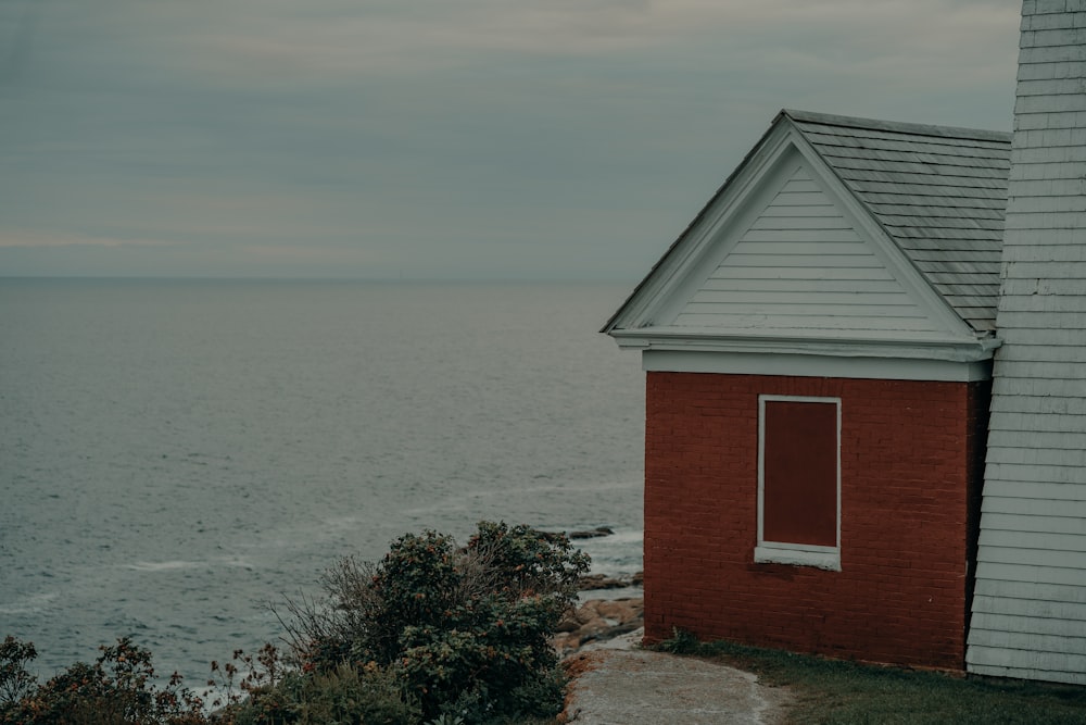 a red building sitting on top of a cliff next to the ocean
