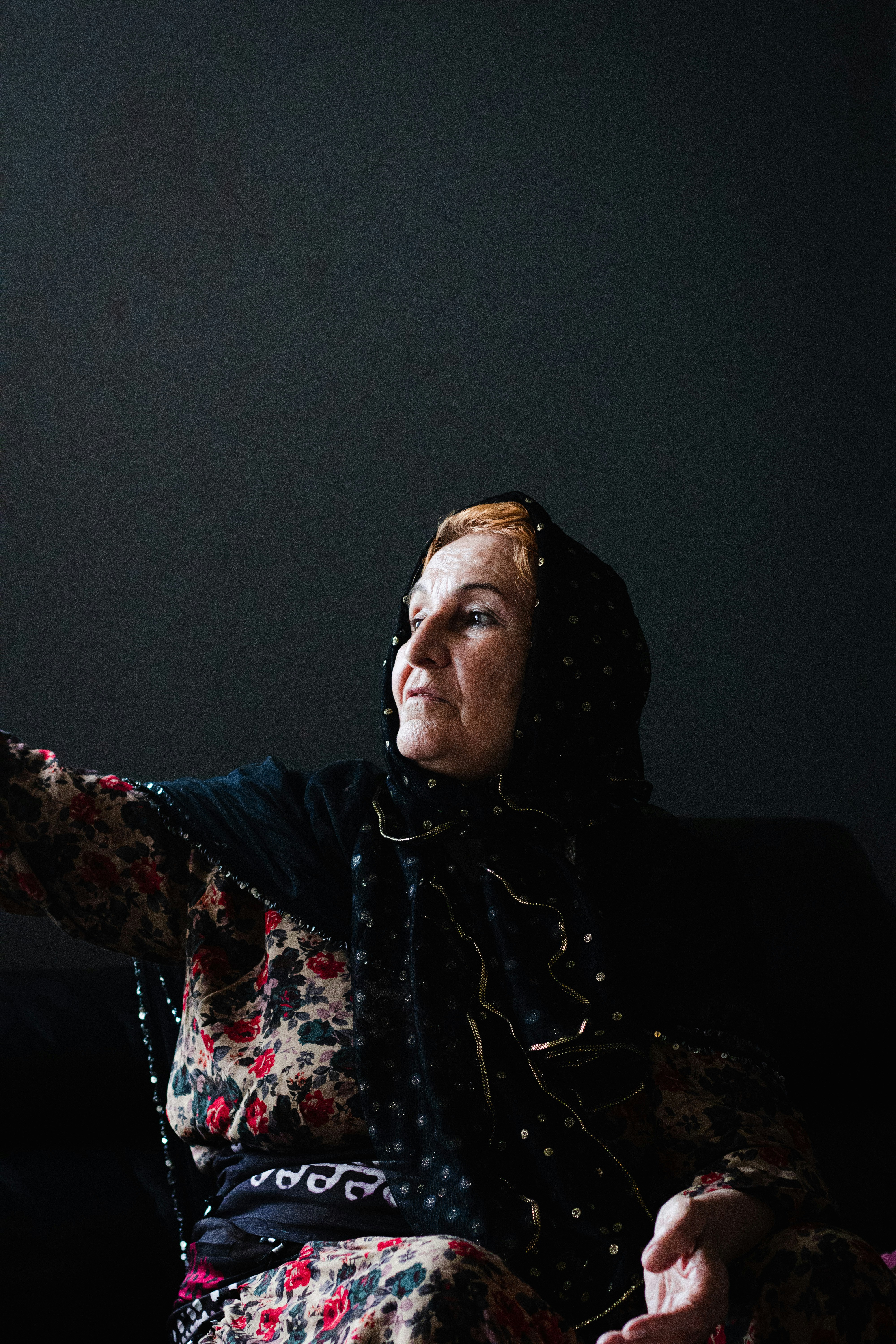 Seorang wanita duduk di sofa memegang remote control