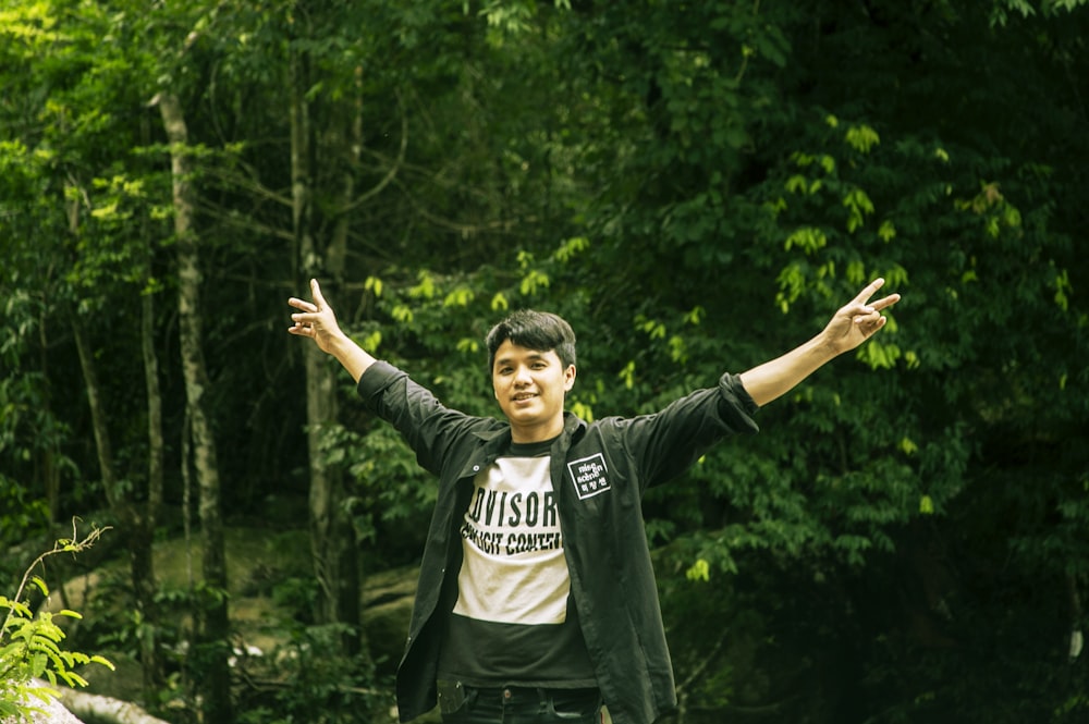 a man standing in front of a lush green forest