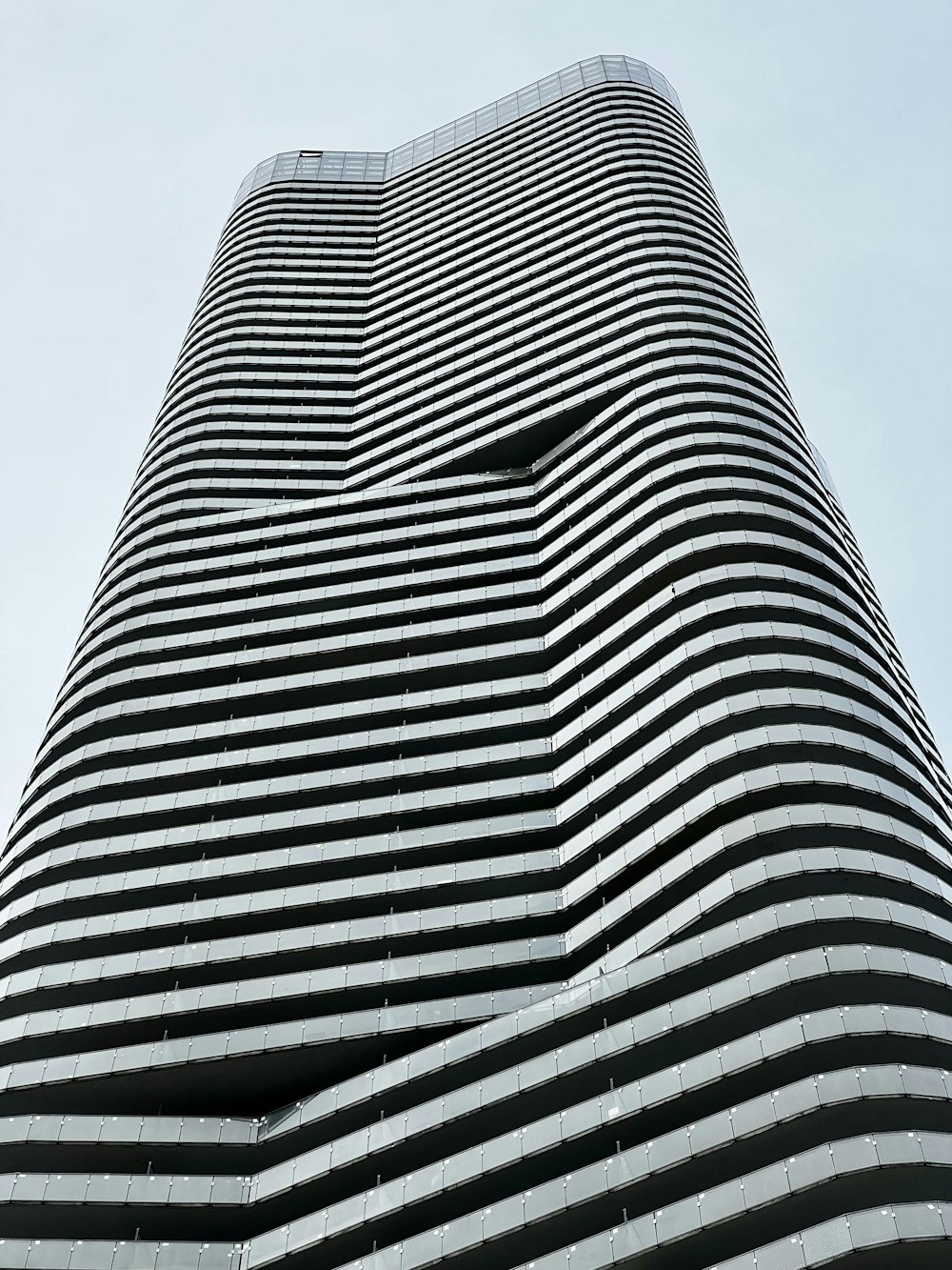 a tall black and white building with a sky background