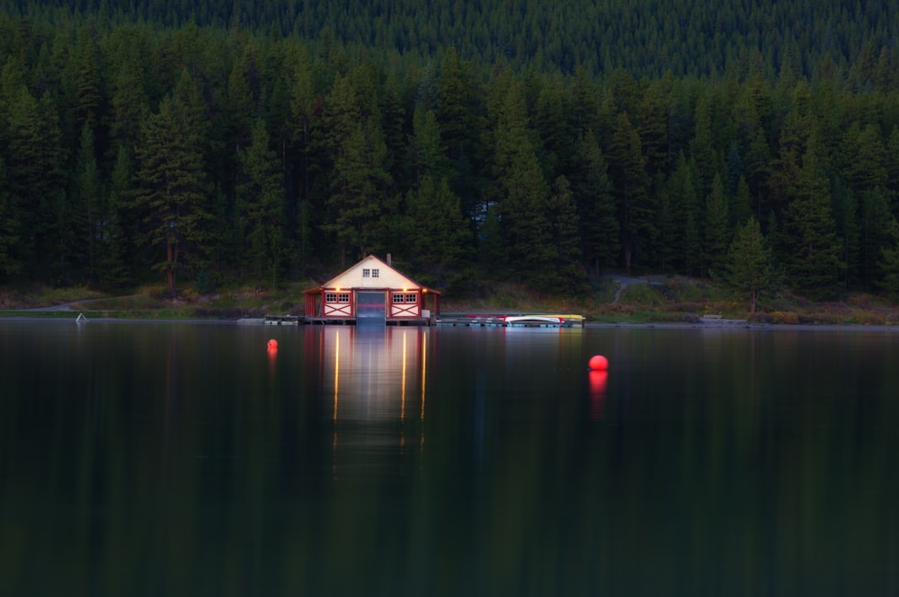 a small house sitting on top of a lake next to a forest