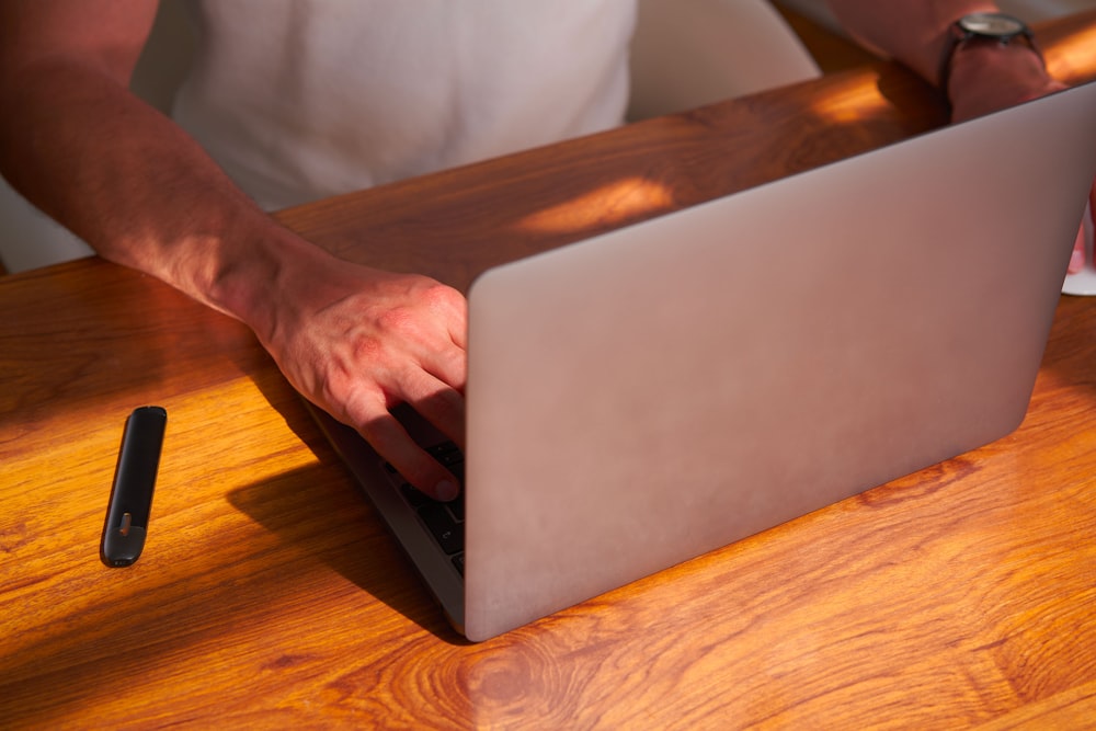 a person using a laptop on a wooden table
