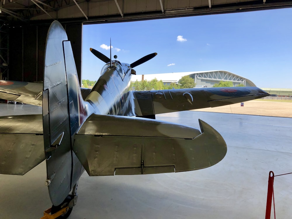 a propeller plane sitting inside of a hangar