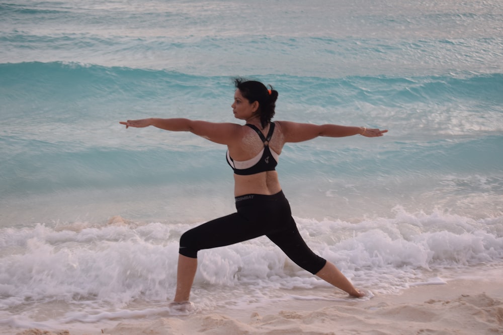 a woman is doing yoga on the beach