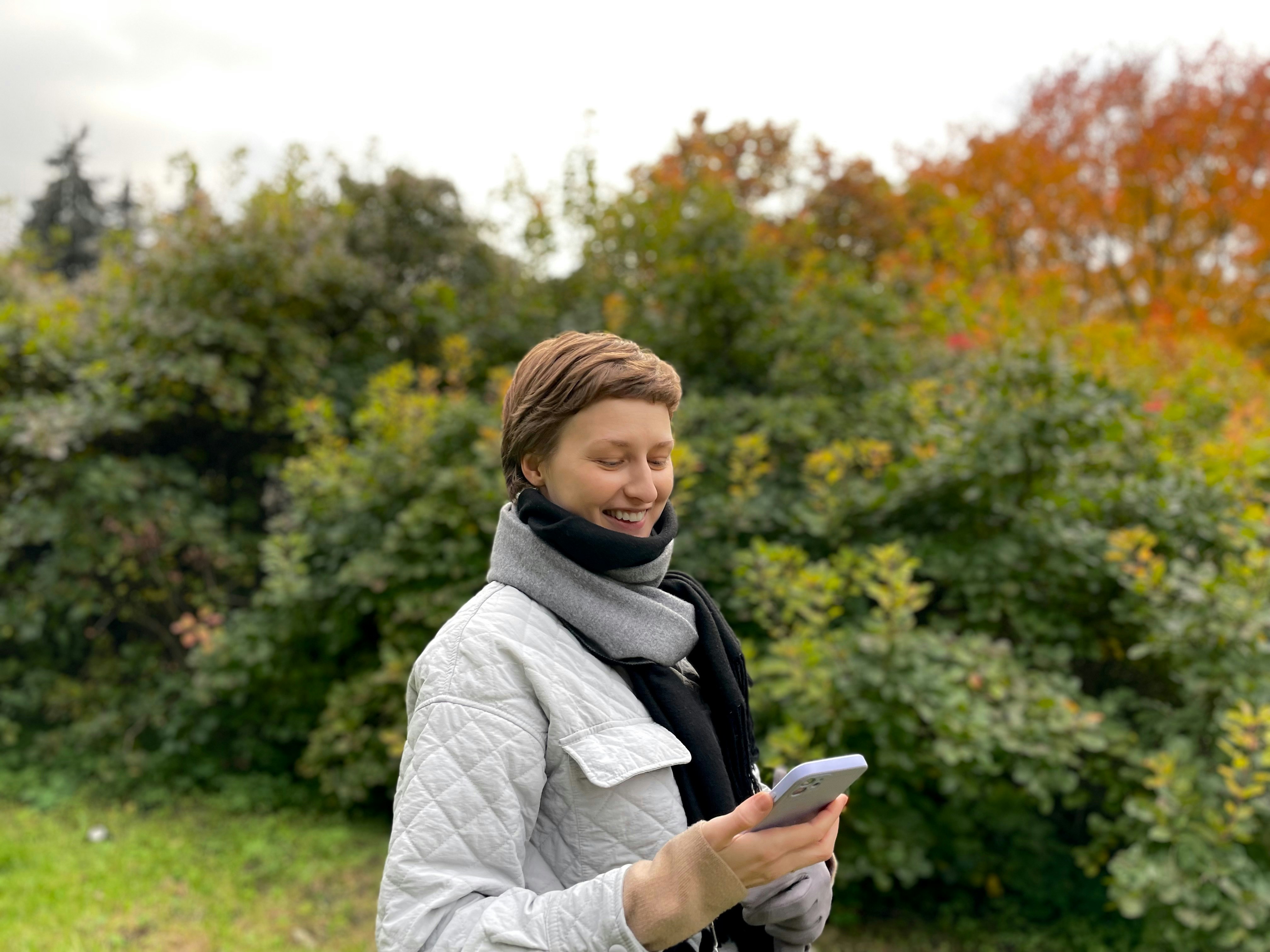 a woman standing in a field looking at her cell phone