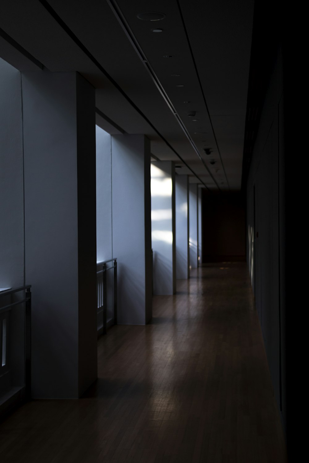 a dark hallway with a row of white doors