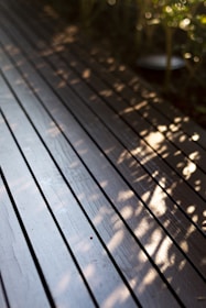 a close up of a wooden deck with plants in the background