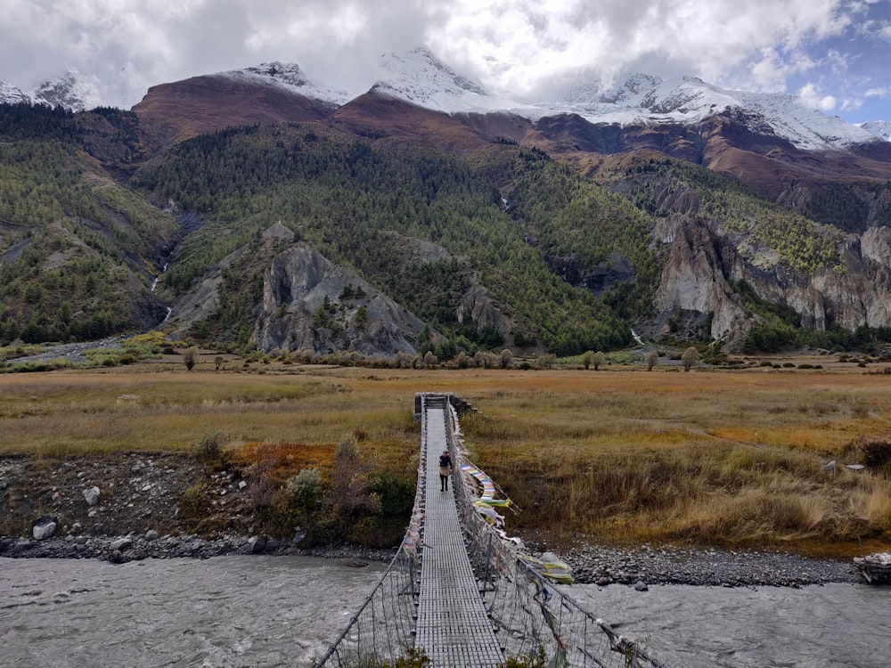 Un ponte sospeso su un fiume con le montagne sullo sfondo