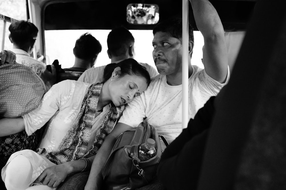 a black and white photo of a woman sleeping on a bus