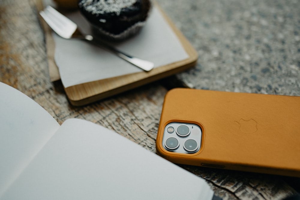 a close up of a cell phone near a cupcake