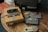 A vintage Super Nintendo Entertainment System (SNES) console sits on a wooden table alongside a CRT television. Four game cartridges are scattered next to the console, one of which is inserted into the system. A classic controller with a beige body and purple buttons is connected to the console.