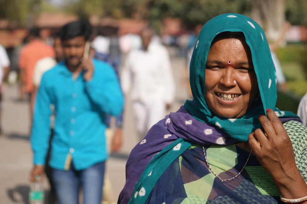 a woman in a headscarf smiles as she walks down the street