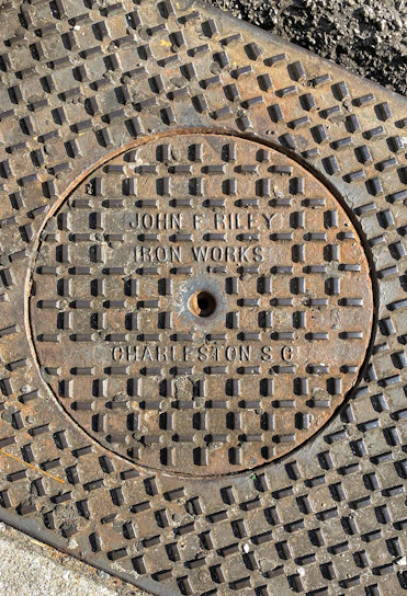A close-up view of a sturdy fiber reinforced polymer manhole cover installed on a busy urban street.