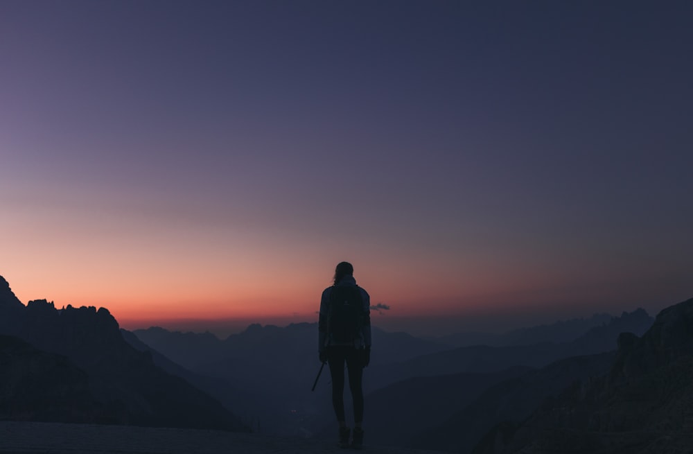 Eine Person, die bei Sonnenuntergang auf einem Berg steht