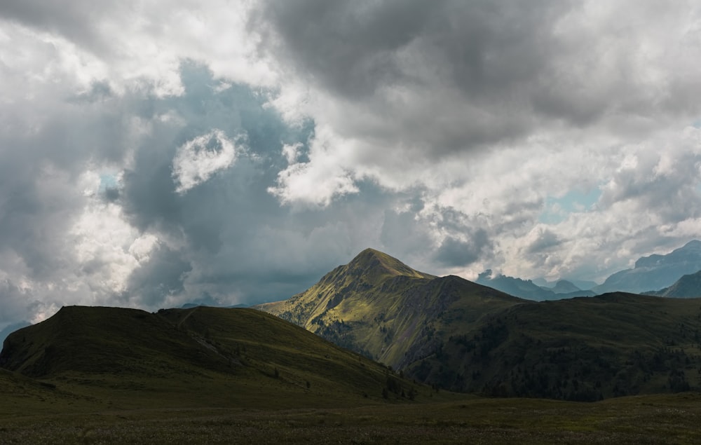 a mountain range under a cloudy sky with clouds